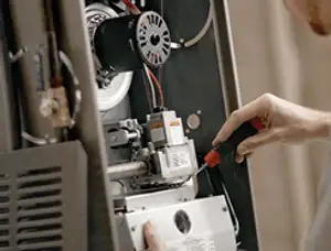 Furnace repair technician inspecting internal components and wiring in Columbus, OH