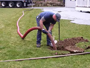 Septic pumping technician servicing a residential septic tank with a vacuum hose in Columbus, OH