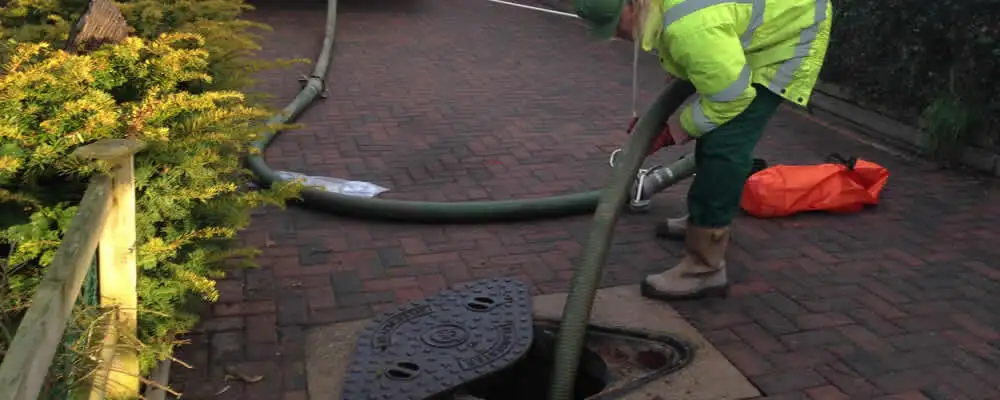 Septic tank cleaning technician servicing a septic tank with a vacuum hose in Columbus, OH