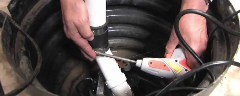 Sump pump installation technician connecting PVC discharge piping in Columbus, OH