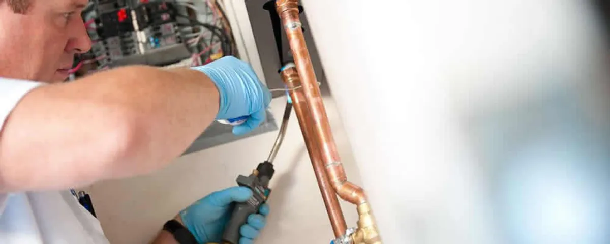 Water heater repair technician testing copper pipe connections and controls in Columbus, OH