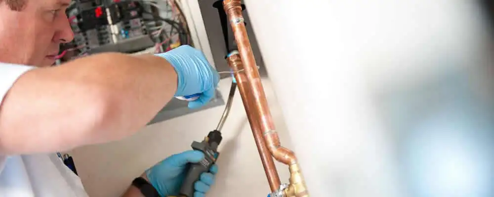Water heater repair technician testing copper pipe connections and controls in Columbus, OH